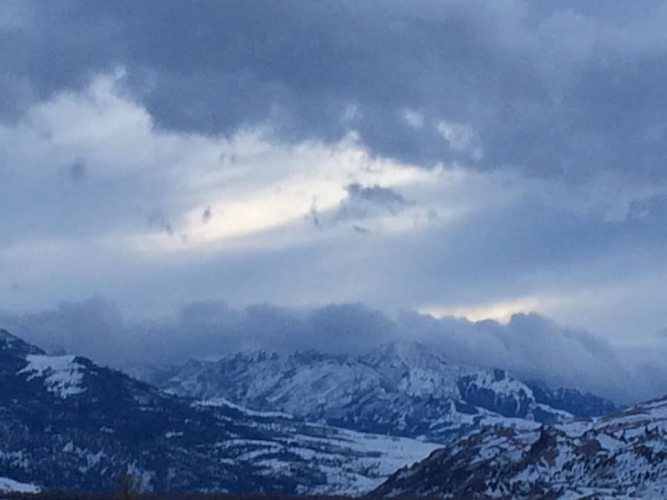 A snowy mountain range with a cloudy sky in the background.