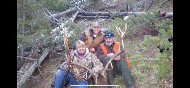 A group of people are posing for a picture with their deer.