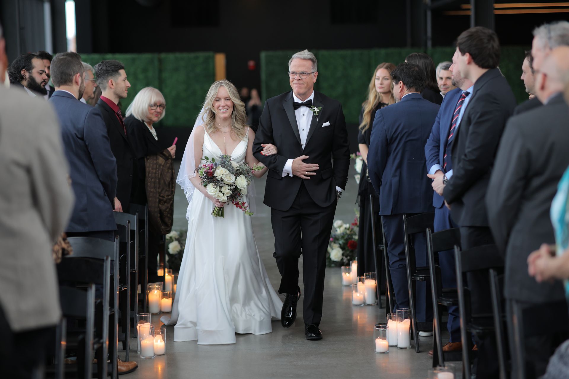 Bride walks down aisle with father, ceremony in a modern space, surrounded by guests.
With Love, Wedding management, Milwaukee Wedding Coordinator