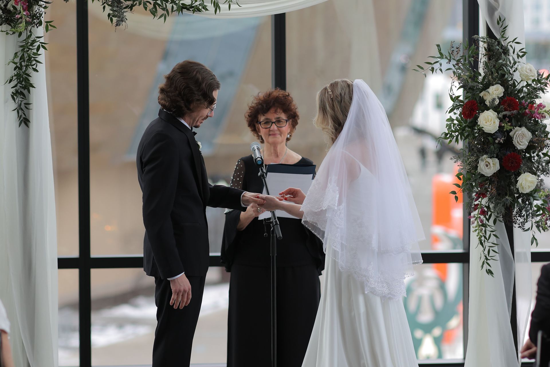 Wedding ceremony: couple exchanging rings; officiant stands between. Modern venue, bright.
With Love, Wedding management, Milwaukee Wedding Coordinator
