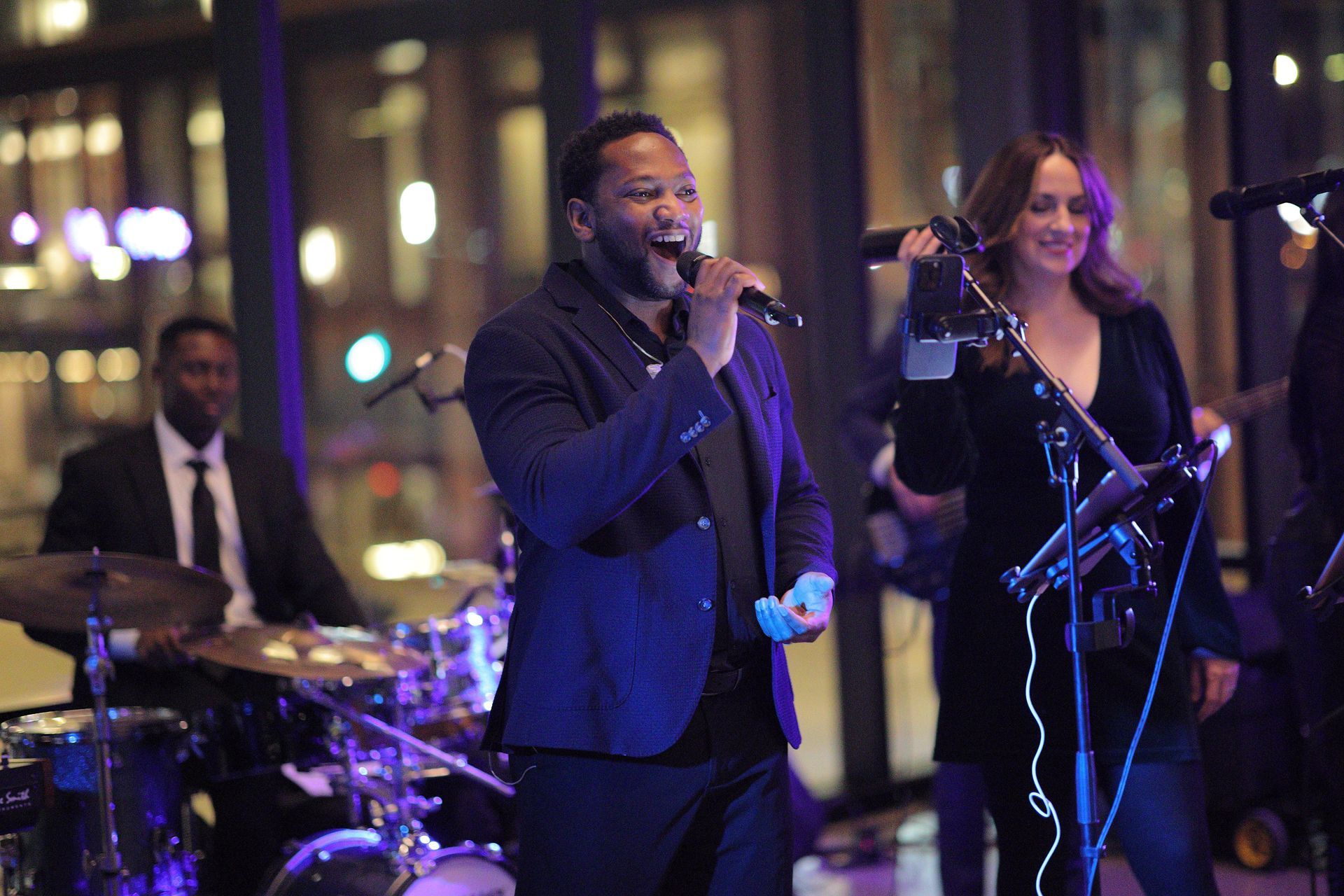 A band performs at night: a male singer, female singer, drummer, and guitarist perform with city lights in background.
With Love, Wedding management, Milwaukee Wedding Coordinator