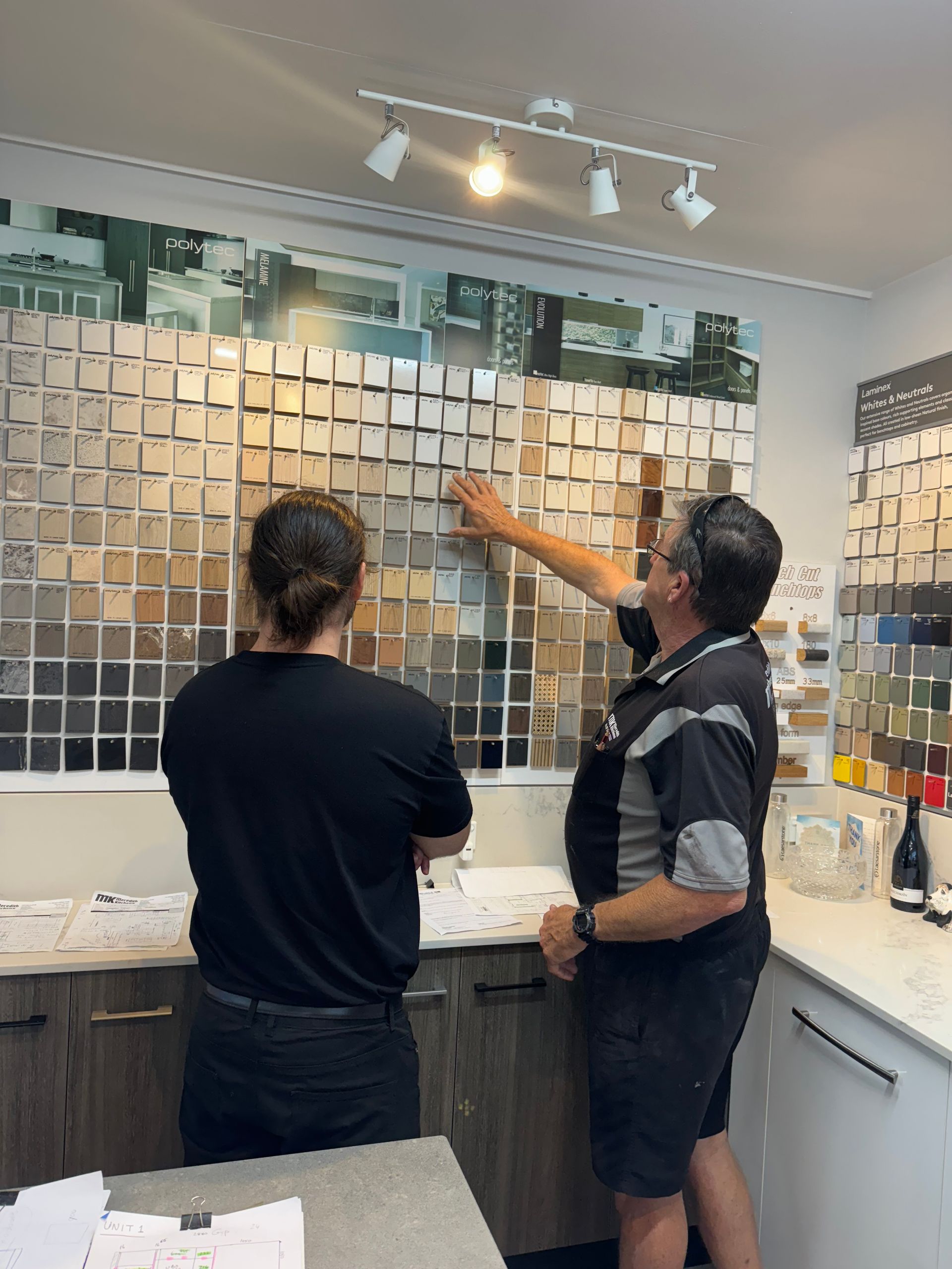 Two People Standing Looking At Colour Swatches In A Showroom — Meredith Kitchens In Moffat Beach, QLD
