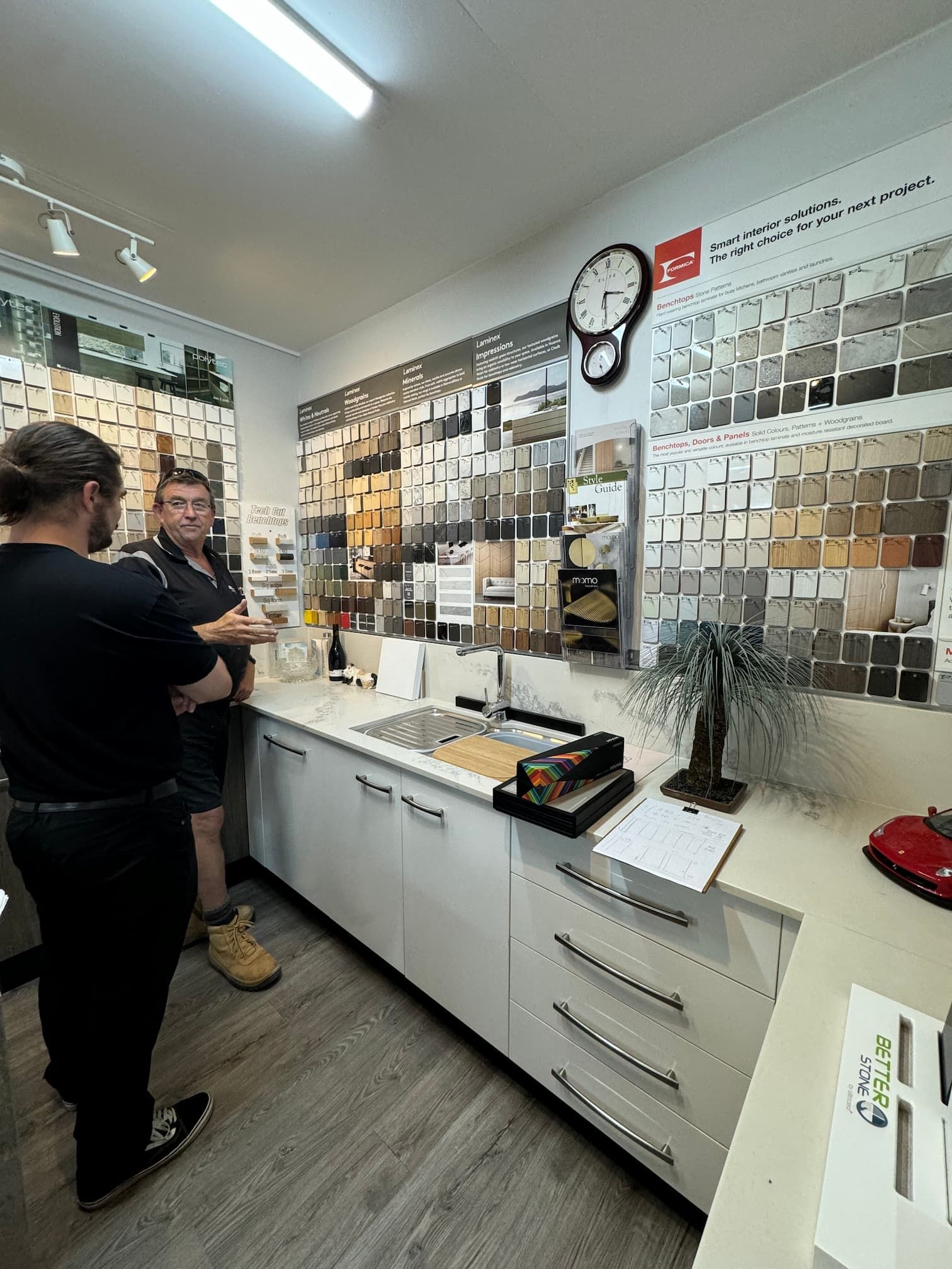A Showroom With Colour Swatches and Two People Standing — Meredith Kitchens In Moffat Beach, QLD