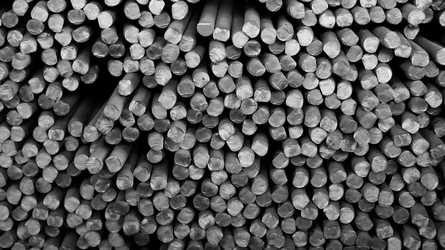 Una foto in bianco e nero di una pila di barre di metallo accatastate l'una sull'altra.