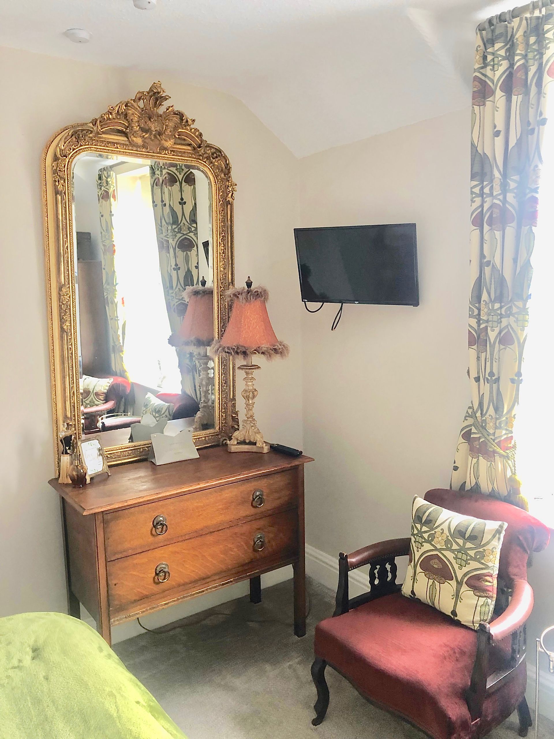 A bedroom with a bed , chair , dresser , mirror and television.