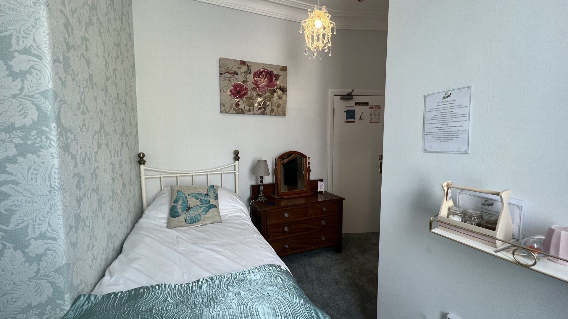 A bedroom with a single bed , dresser and mirror.