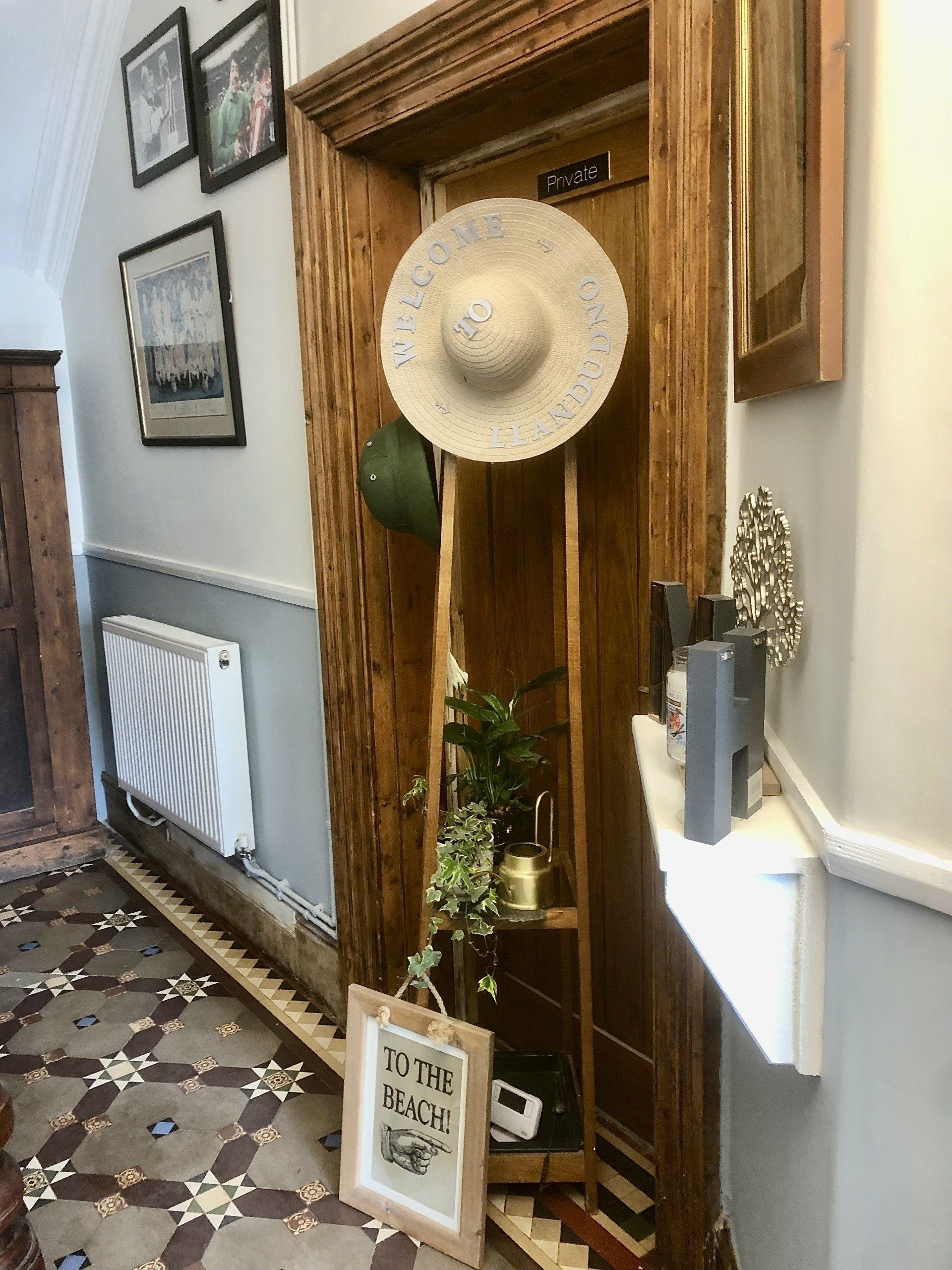 A hat is hanging on a wooden rack in a hallway.