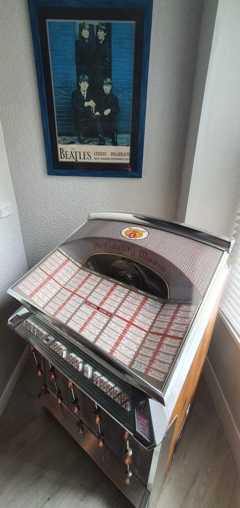 A jukebox is sitting in a room next to a picture on the wall.