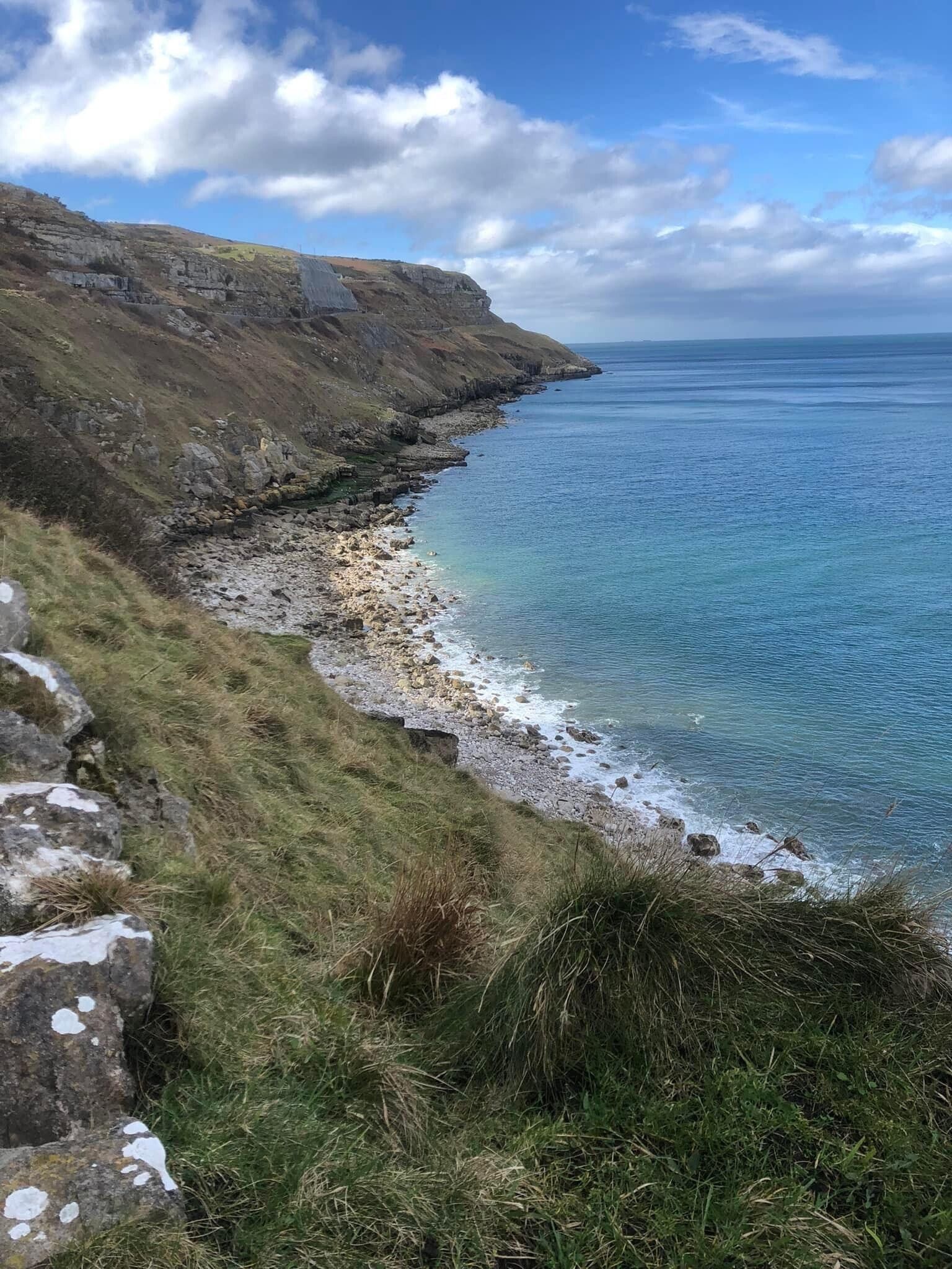 A cliff overlooking a body of water on a sunny day.