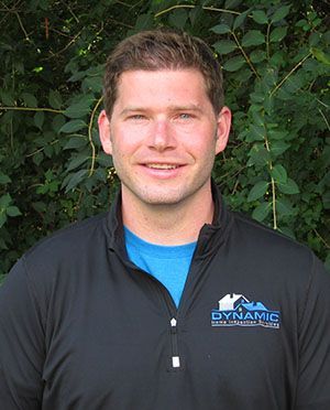 A man wearing a black jacket and a blue shirt is smiling for the camera.