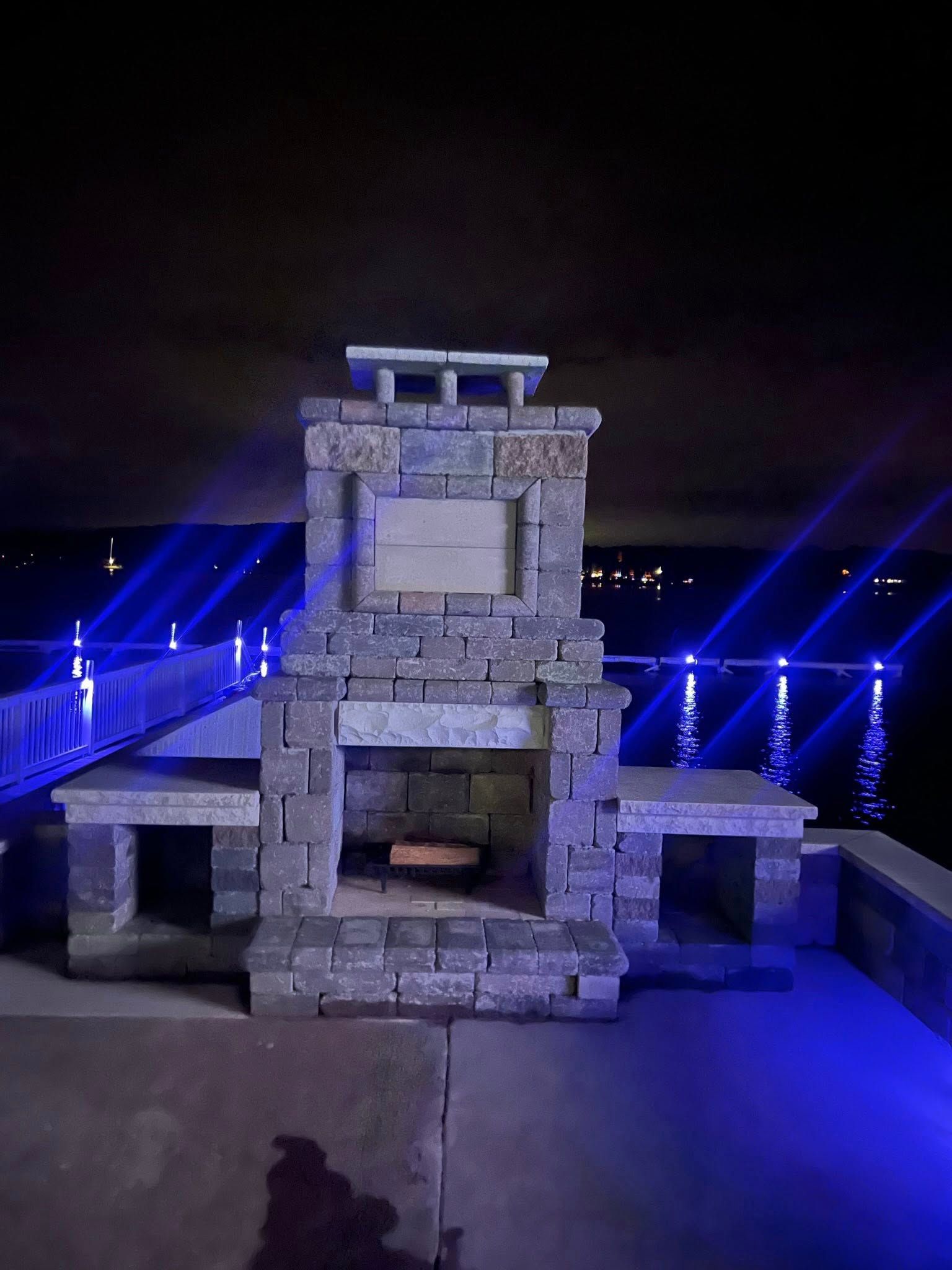 A brick fireplace is lit up at night with blue lights.
