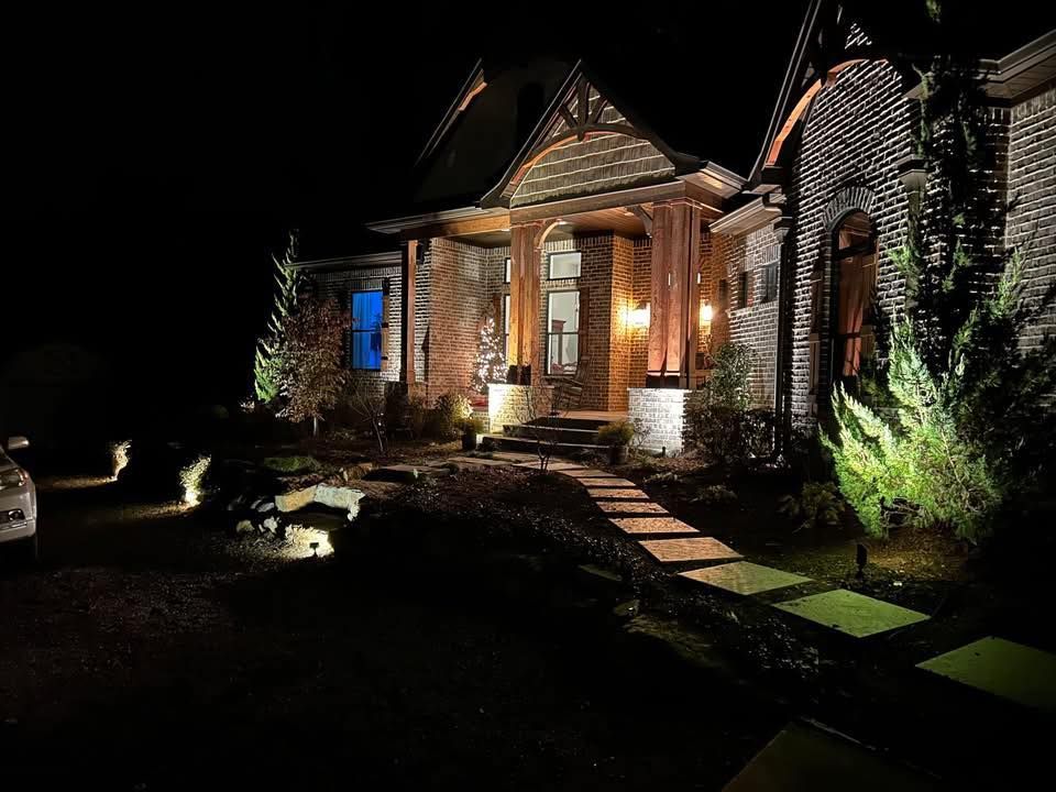 A house is lit up at night with a car parked in front of it.