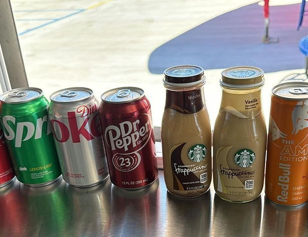 A row of cans and bottles of soda on a table.