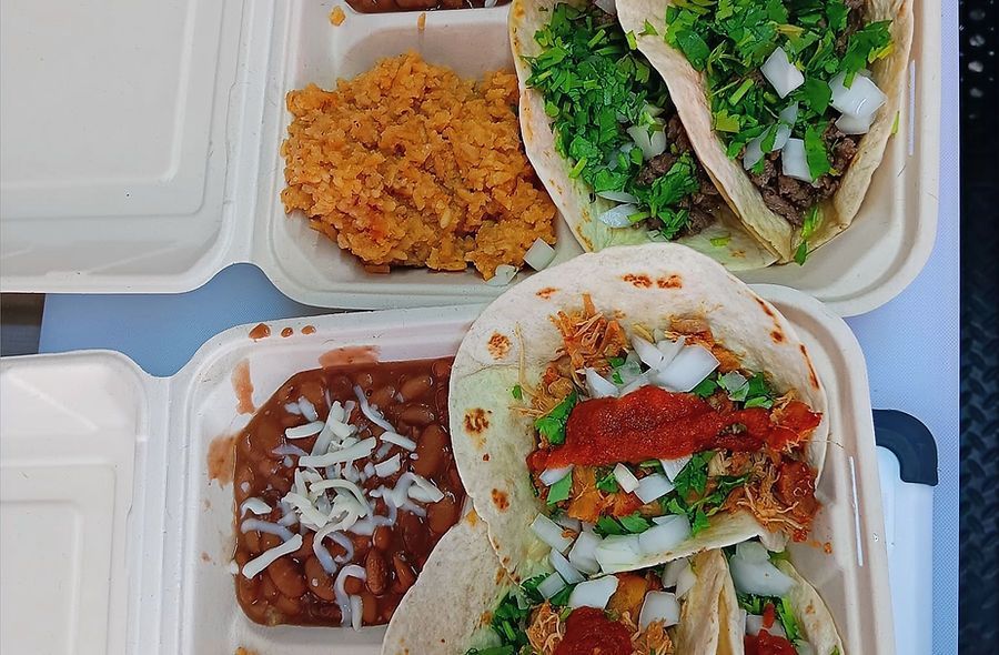 Two styrofoam containers filled with tacos and beans on a table.