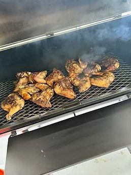 Chicken is being cooked on a grill with smoke coming out of it.