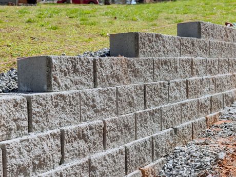 A brick wall is being built on top of a grassy hill.