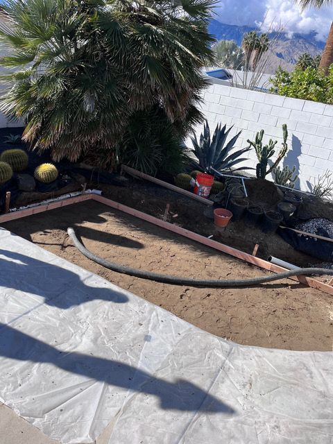 A hose is laying in the dirt in a garden.