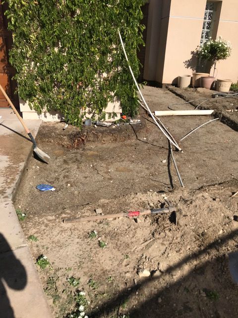 A person is digging in the dirt in front of a house