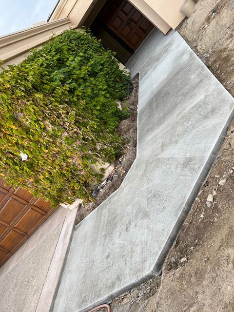 A concrete walkway is being built in front of a house.