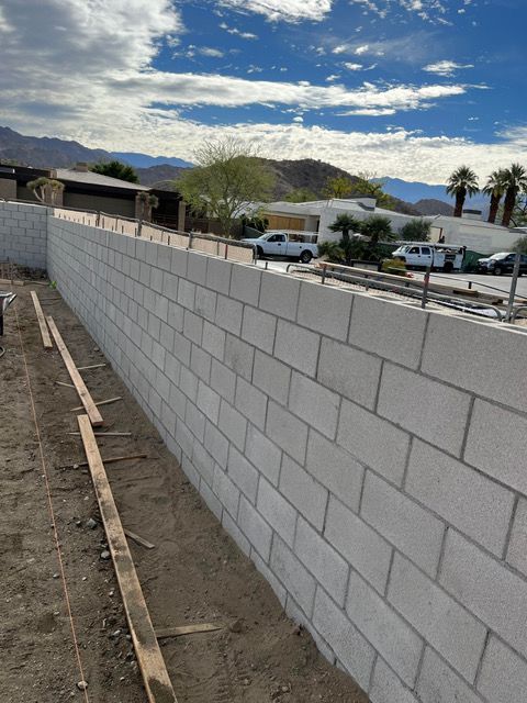 A brick wall is being built in front of a house.