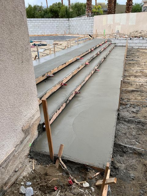 A concrete walkway is being built in front of a house.
