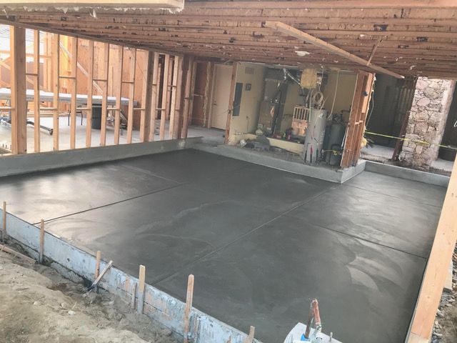 A concrete floor is being poured in a garage under construction.