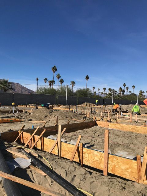A construction site with a blue sky and palm trees in the background