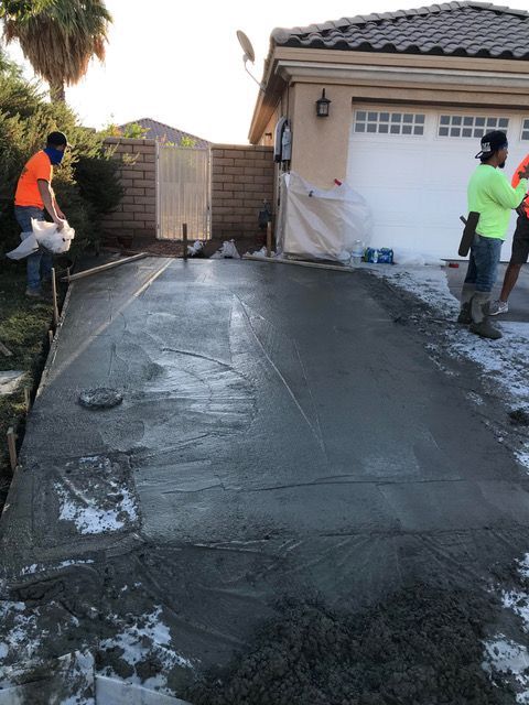 A concrete driveway is being poured in front of a house