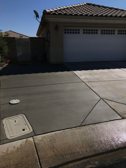 A concrete driveway in front of a house with a white garage door