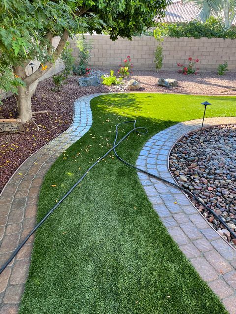 A hose is connected to a brick walkway in a backyard.