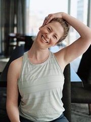 A woman wearing sunglasses is smiling for the camera while sitting on a couch.