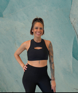 A woman with a tattoo on her arm is wearing a black crop top