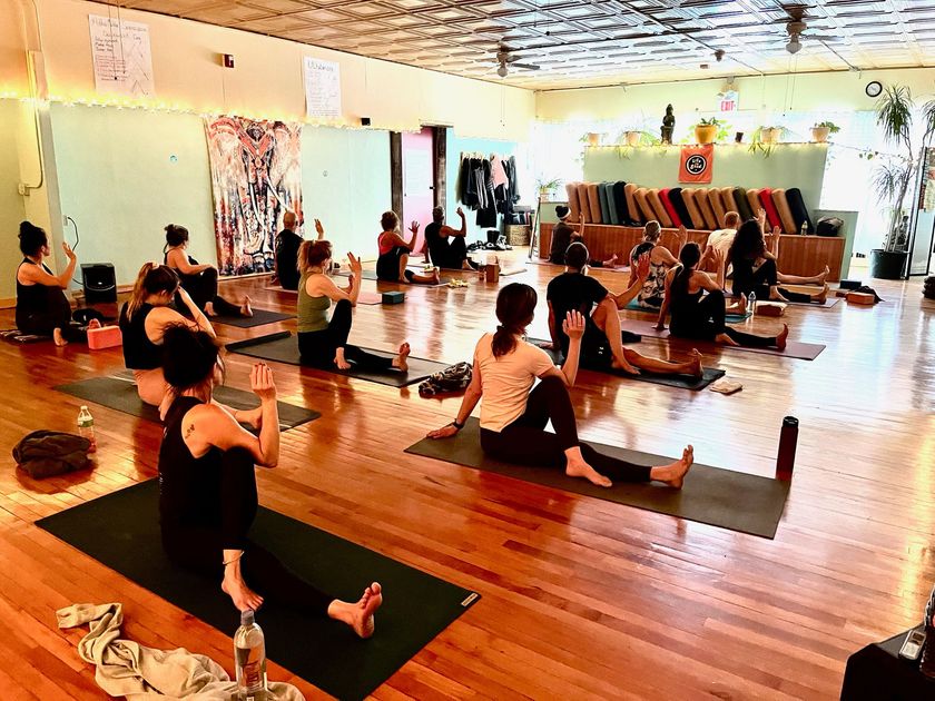 A group of people are sitting on yoga mats in a room.