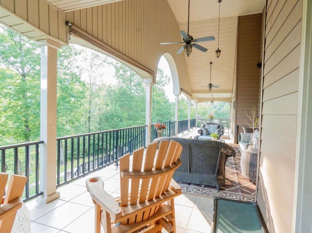 Stone houses with tan roofs line a street under a blue sky with clouds.