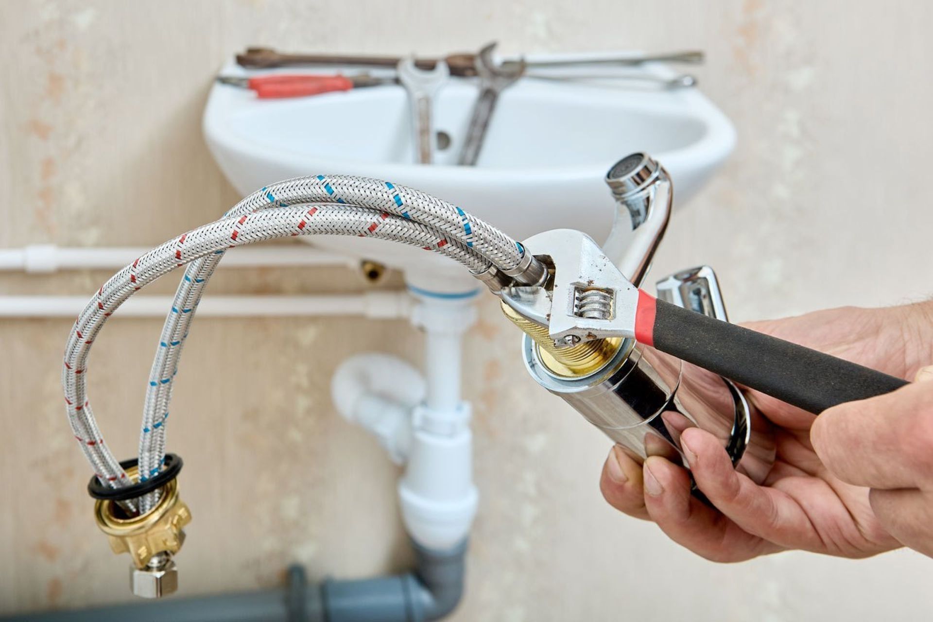 A person is fixing a sink faucet with a wrench.