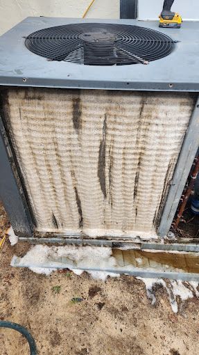 A close up of a dirty air conditioner on the ground.
