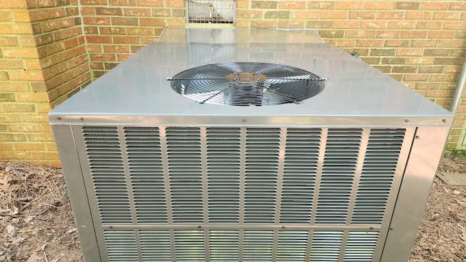 A large air conditioner is sitting outside of a brick building.