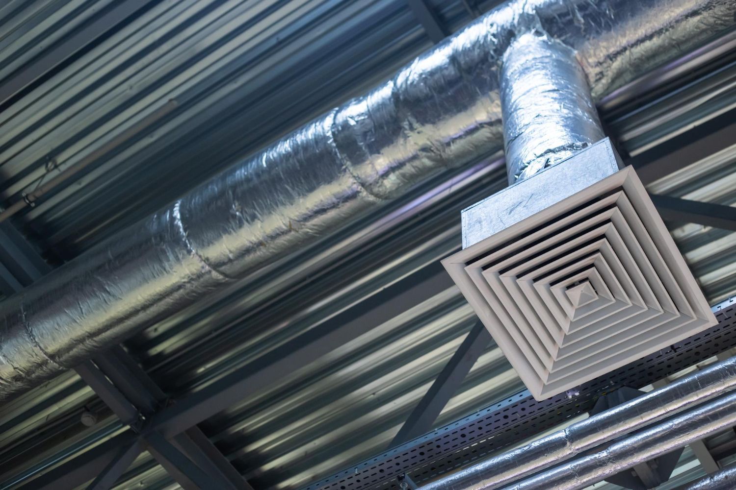 Ceiling ventilation duct and square air vent in an industrial interior