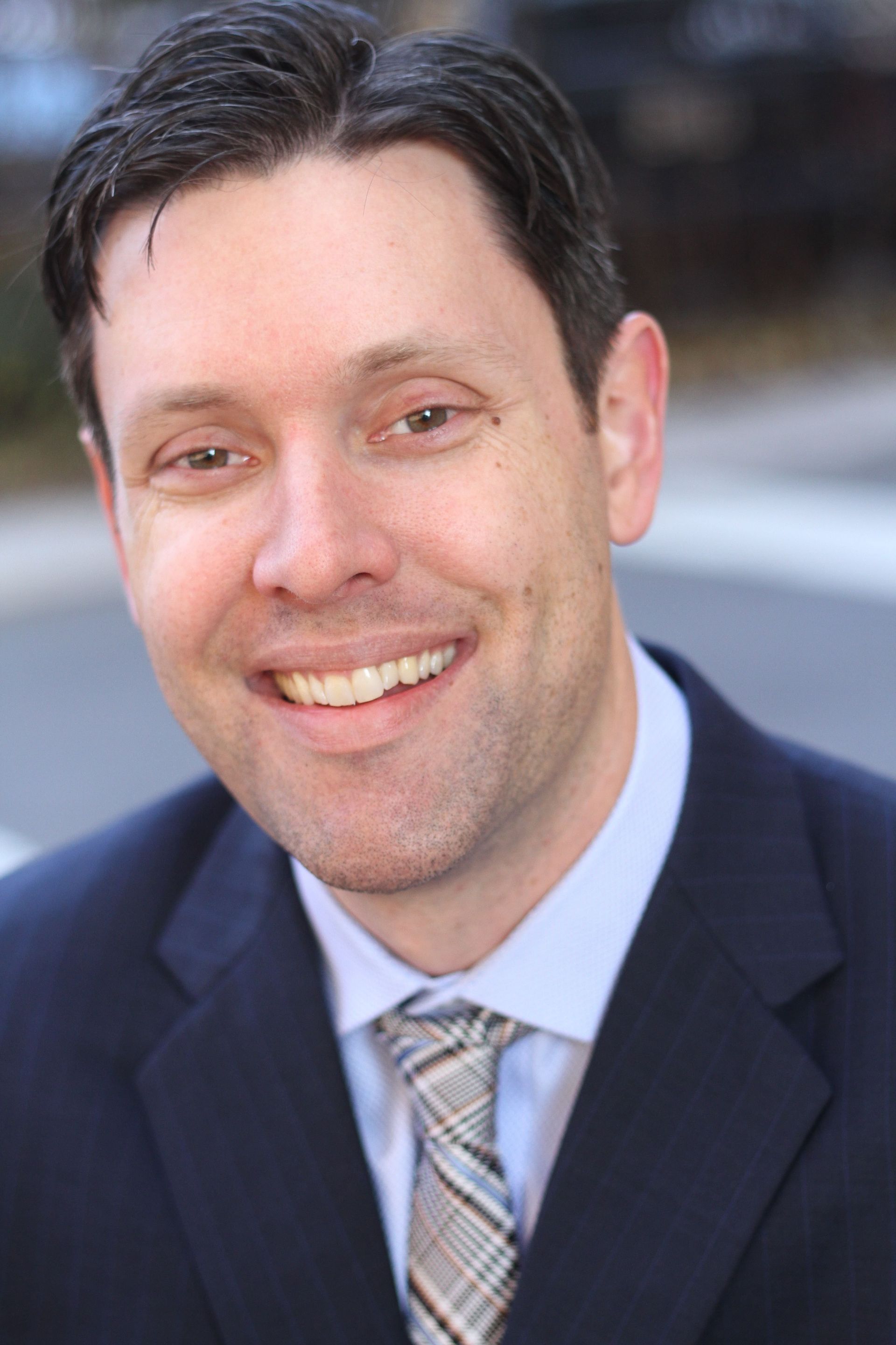 A man in a suit and tie is smiling for the camera