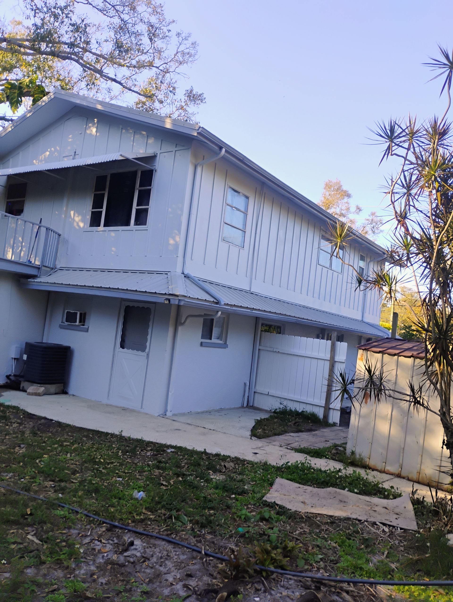 Woman in straw hat smiles, holding wine glass near a lake.