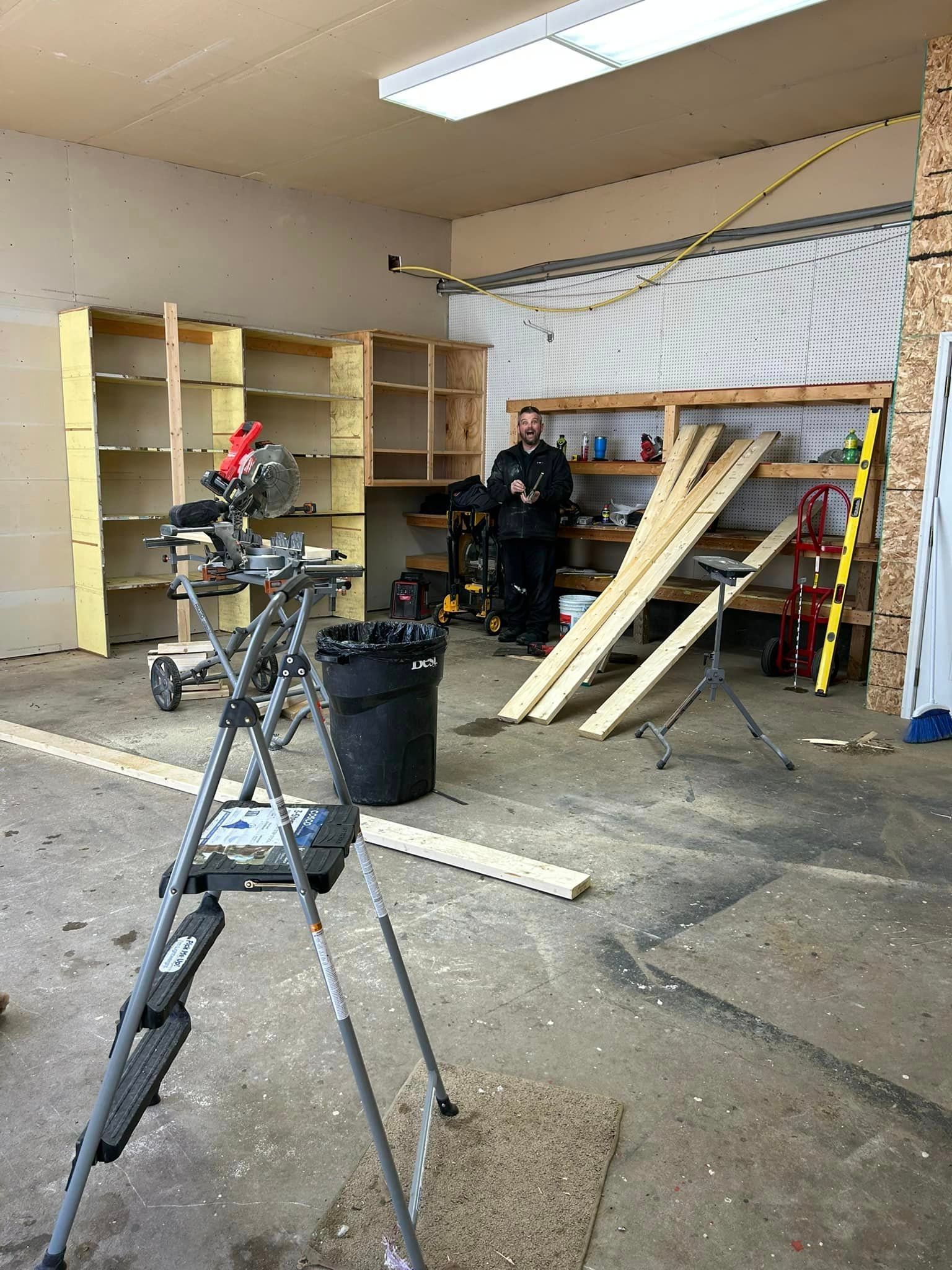 A Man Is Standing In A Garage With A Saw And A Ladder | Park Falls, WI | Park Falls Building
