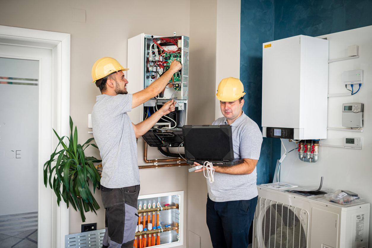 Two men are working on a heating system in a room.
