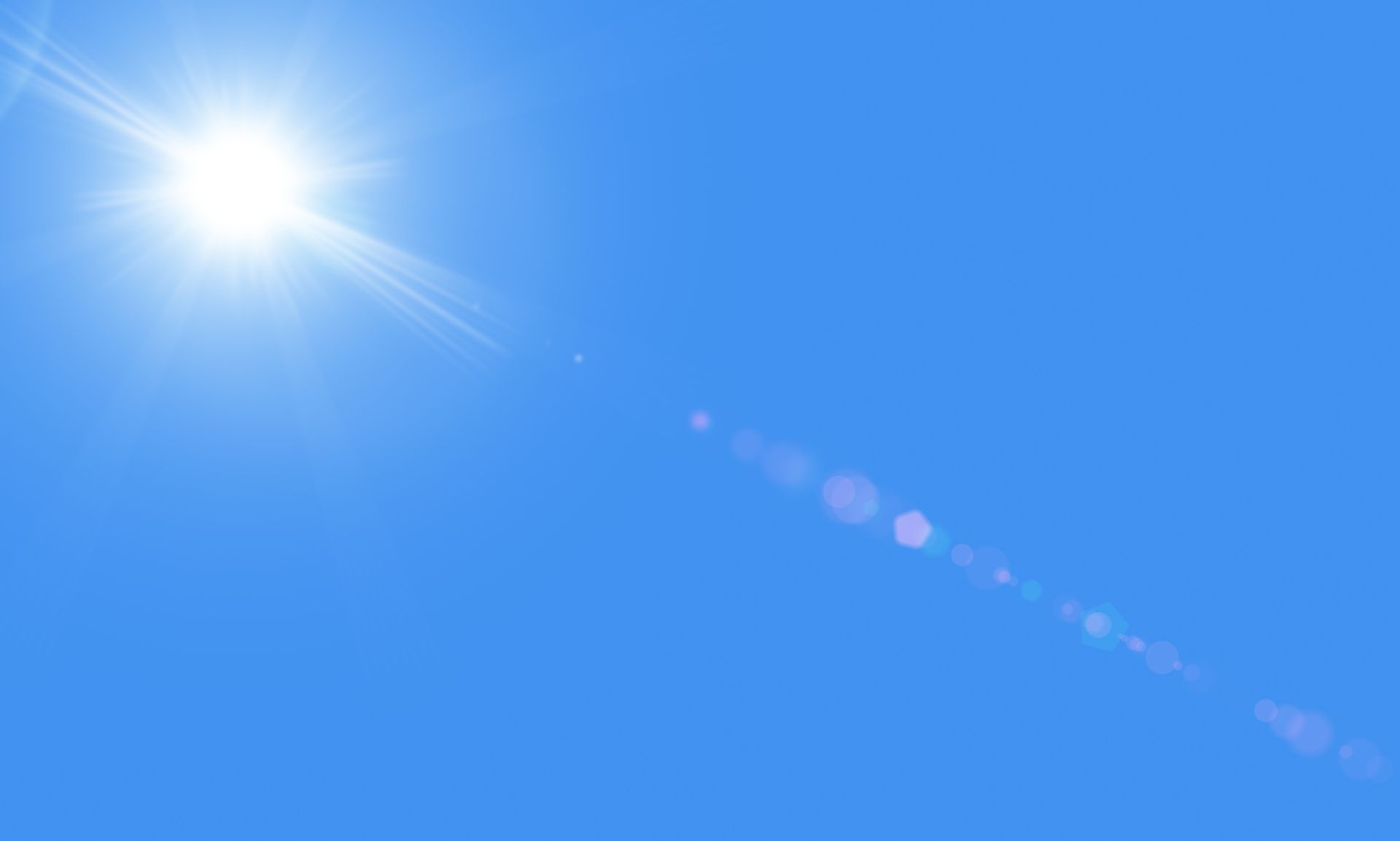 Sun in the blue sky with lensflare.