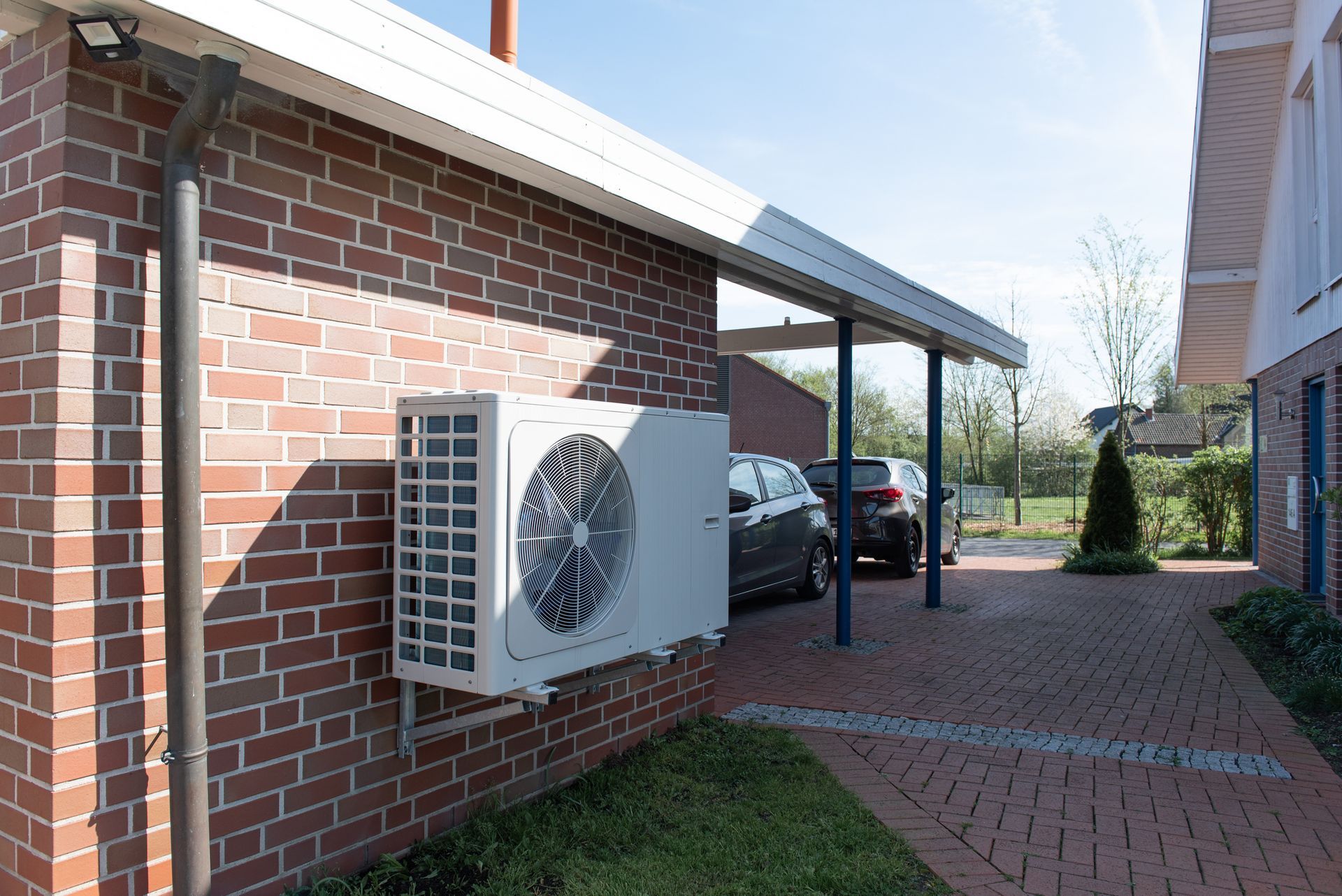 A modern heat pump system installed outside a residential home in warm summer weather.