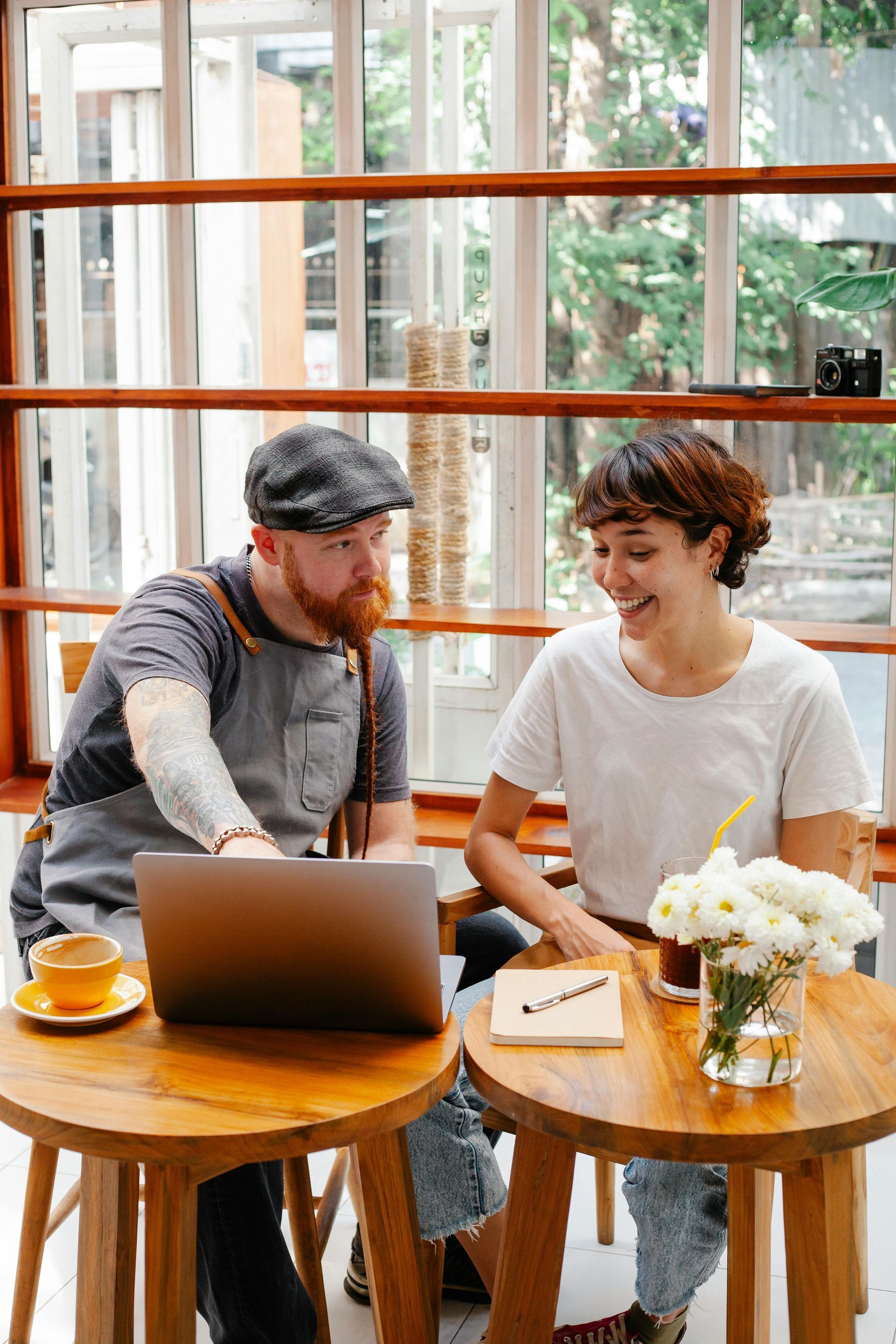 A man and a woman are sitting at a table with a laptop.