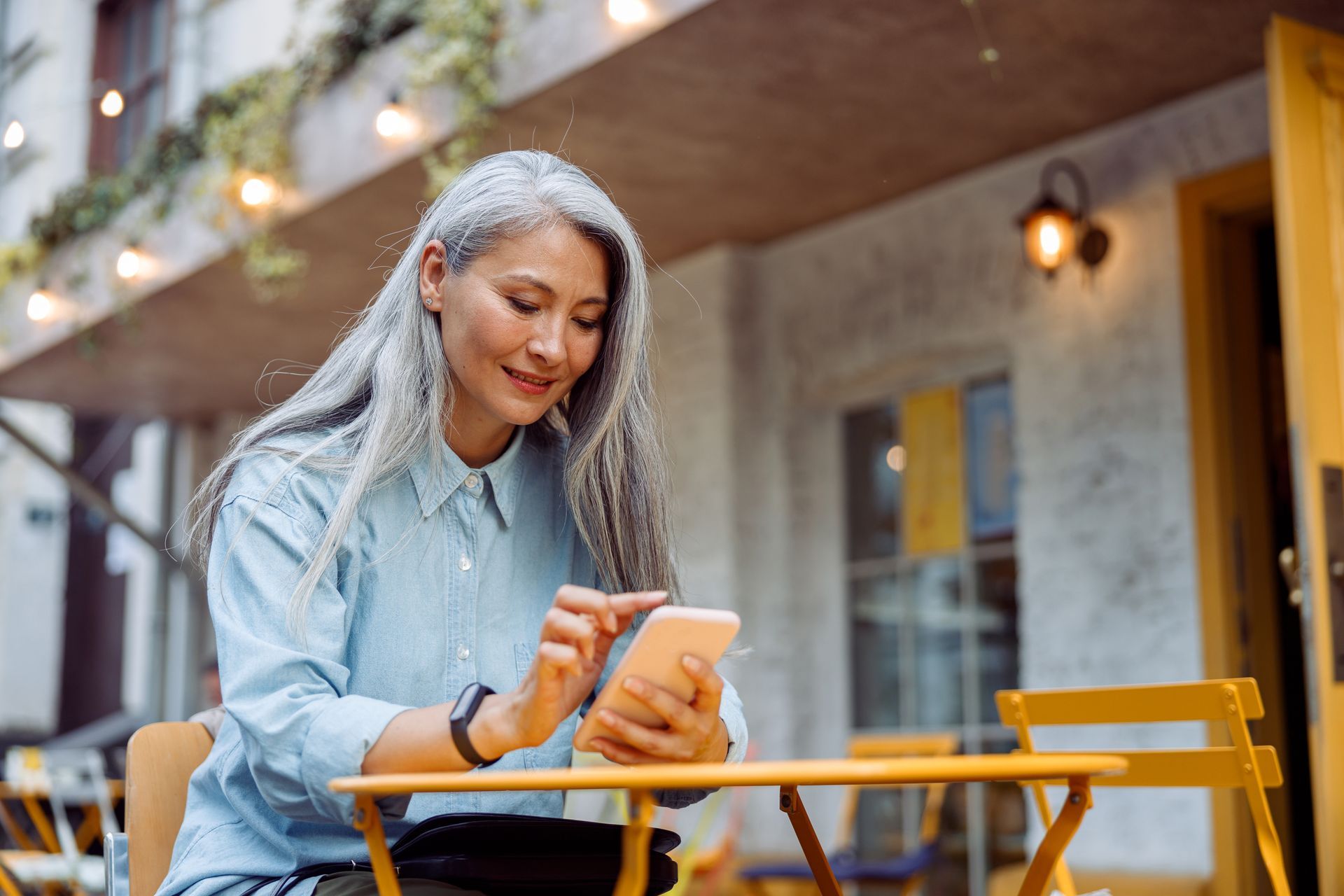A woman is sitting at a table looking at her cell phone.