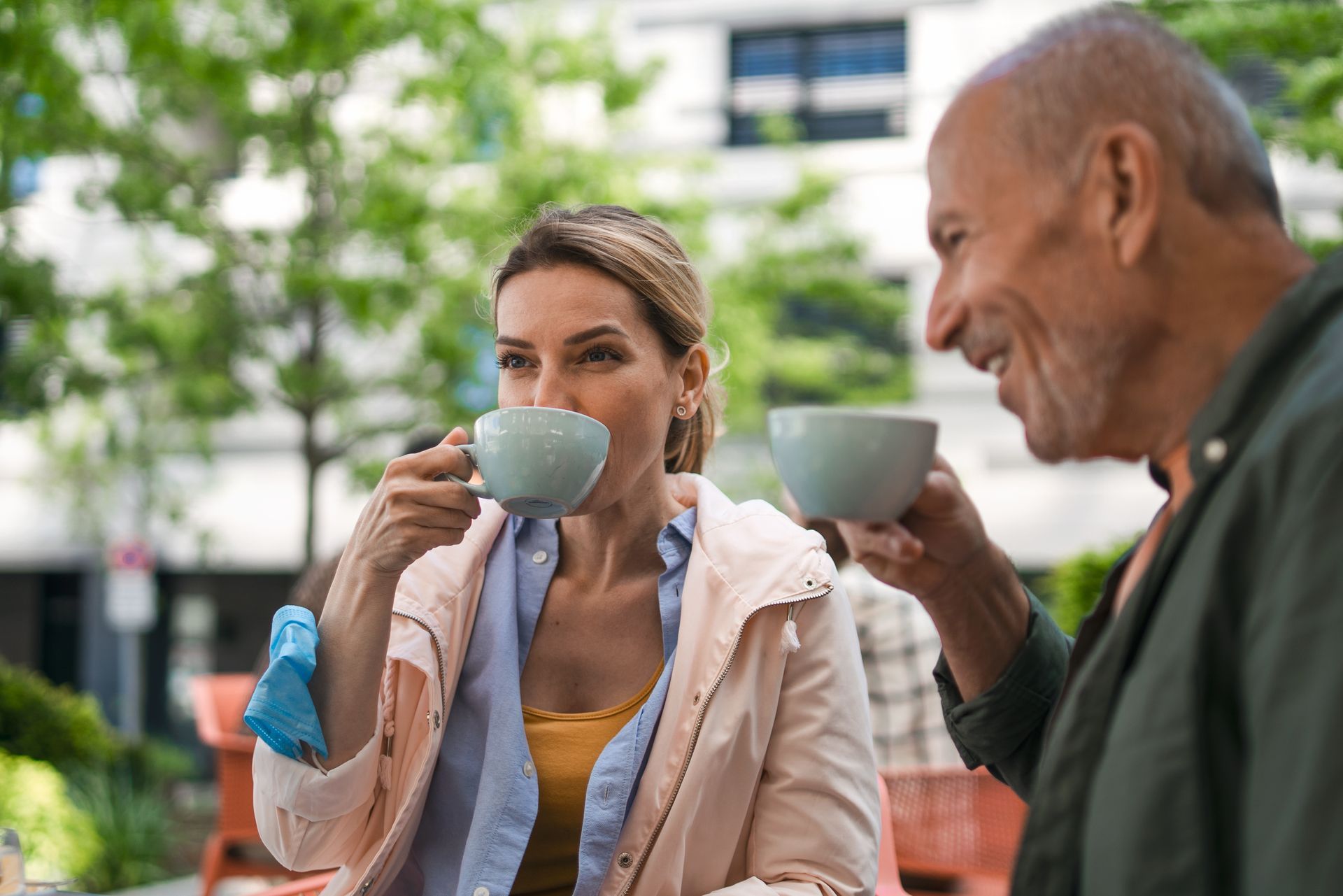 A man and a woman are sitting at a table drinking coffee.