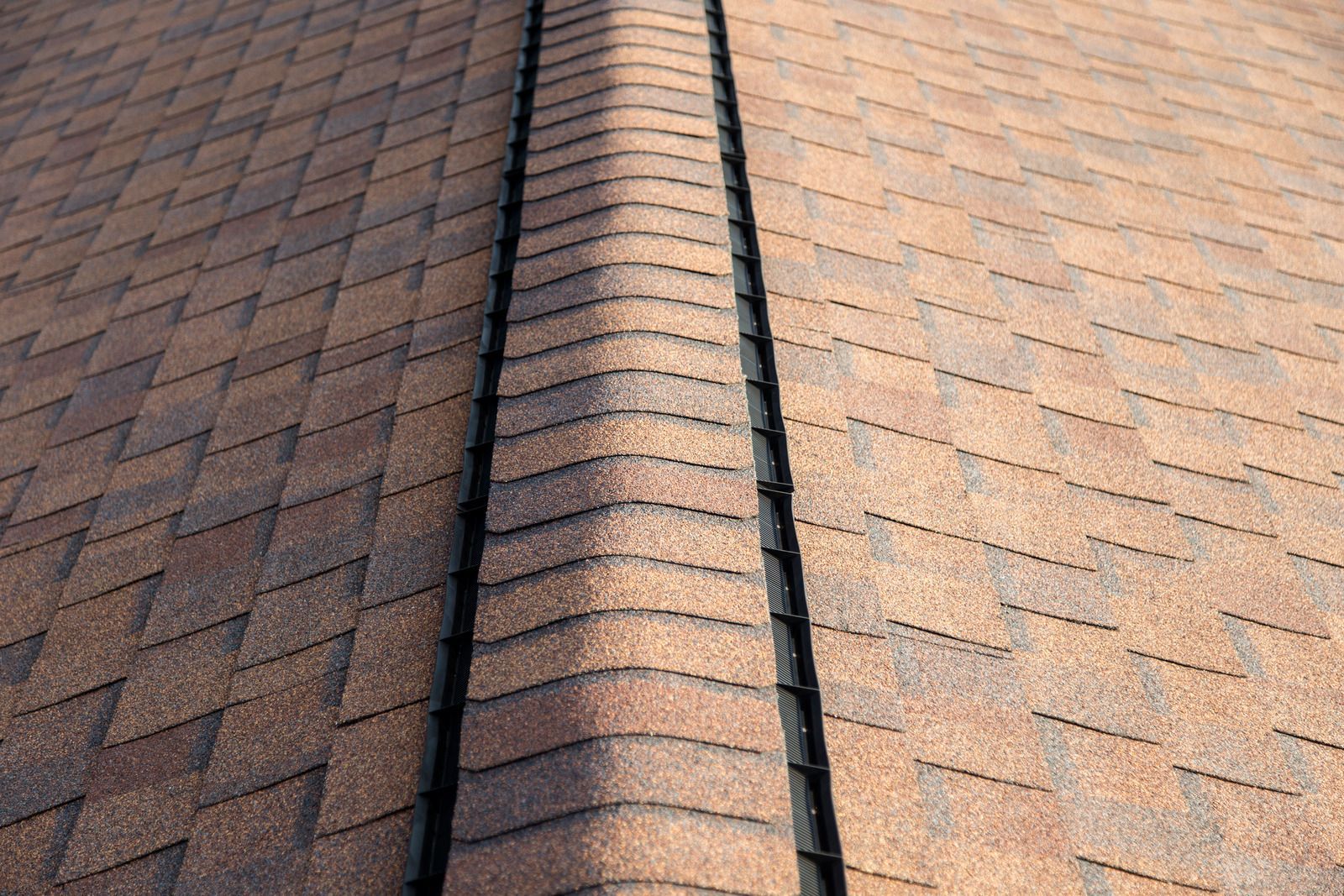 Brown shingle roof with a dark seam. The shingles are laid in rows and angled up.