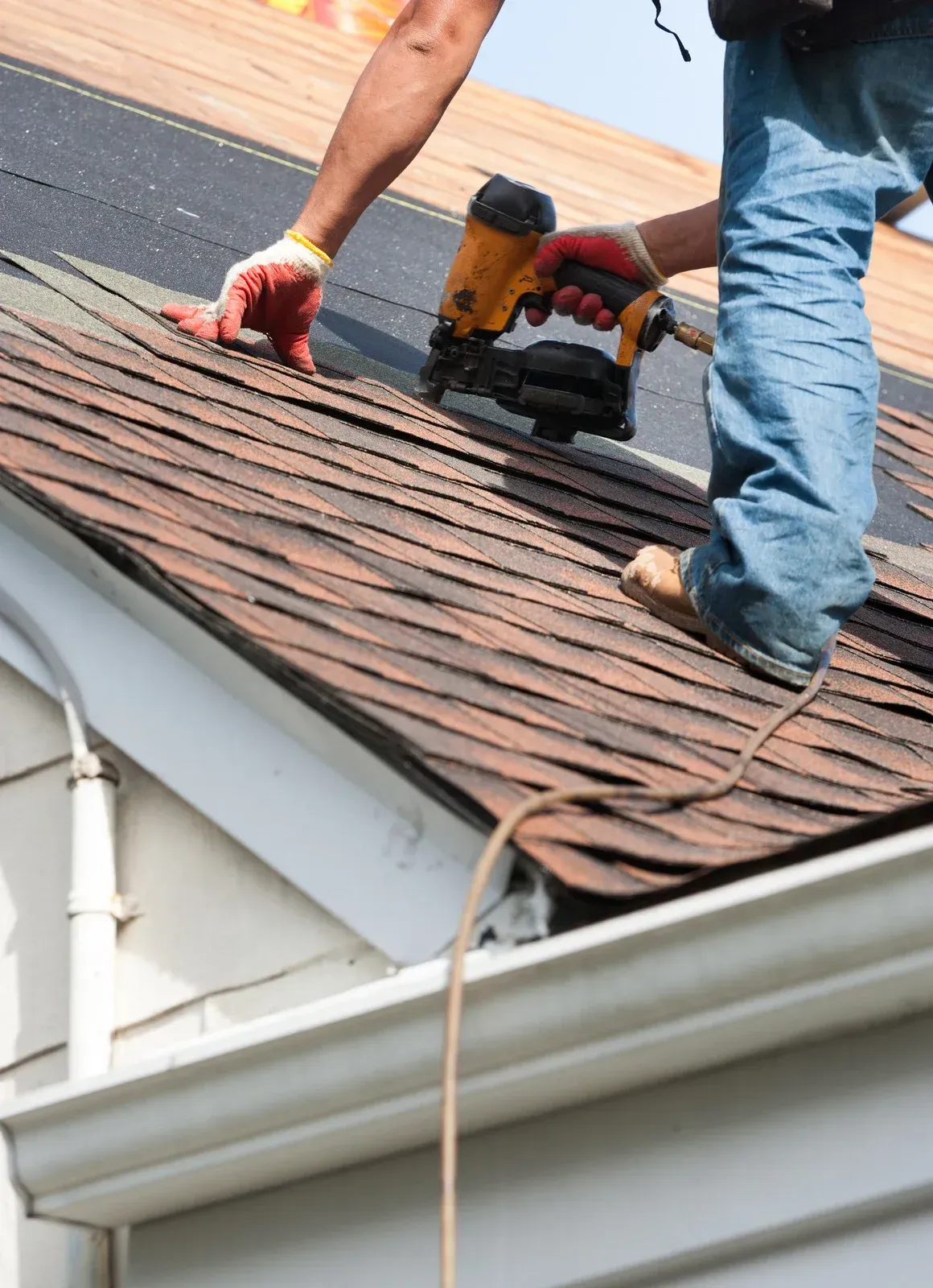 A man is standing on a roof repair a tile