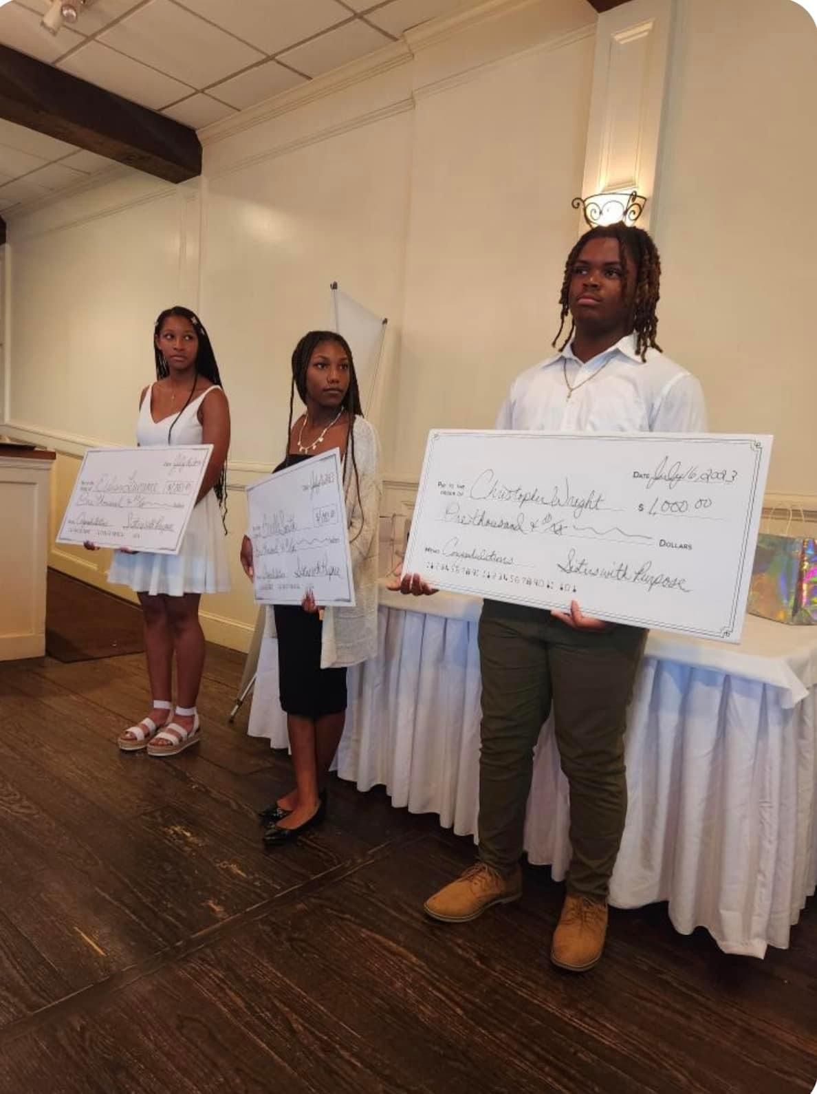 A man and two women are holding checks in front of a table.